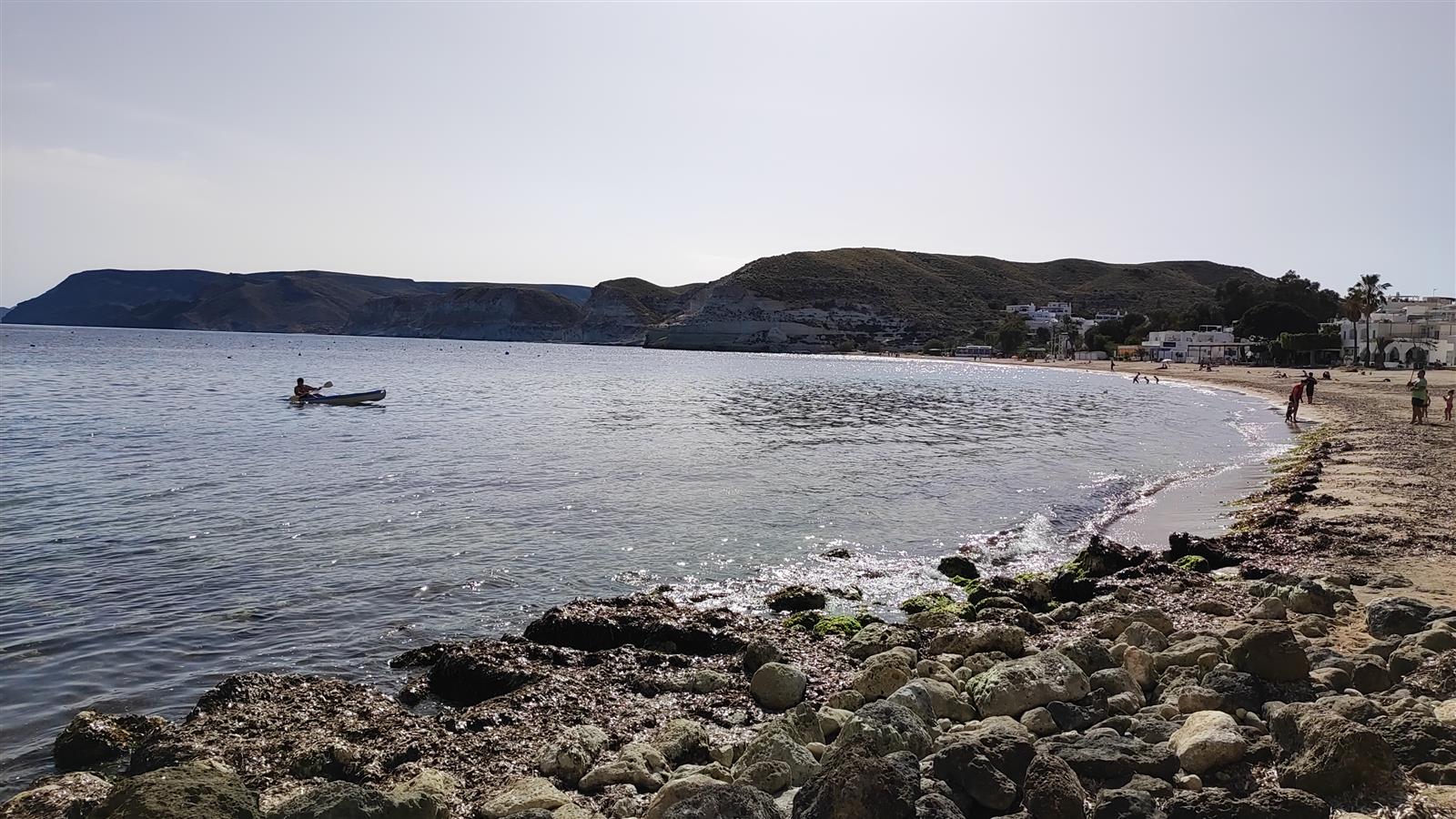 Vista panorámica de la playa de Agua Amarga con arena fina, agua turquesa y acantilados volcánicos al fondo bajo cielo azul