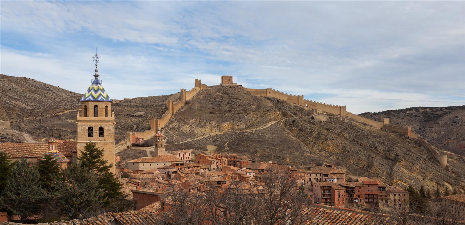 Panorámica de Albarracín desde la ladera: el conjunto medieval de piedra rojiza y ocre con la Catedral y las murallas medievales sobre el meandro del río Guadalaviar, Teruel, Aragón