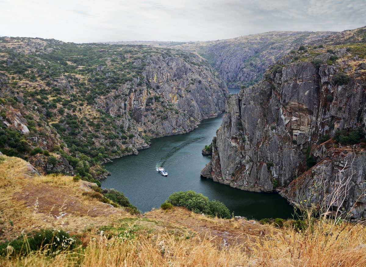Arribes del Duero cerca de Miranda do Douro: panorámica del río Duero con embarcación de crucero en el cañón natural entre España y Portugal