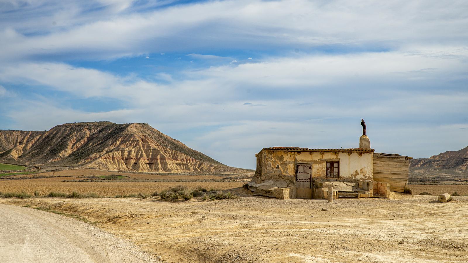 Antigua caseta agrícola junto a una pista de tierra, con un cabezo al fondo