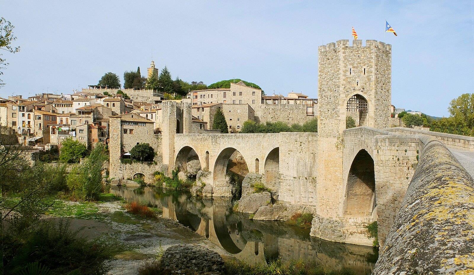 Puente románico medieval de Besalú sobre el río Fluvià con la torre defensiva y el casco histórico al fondo, Girona