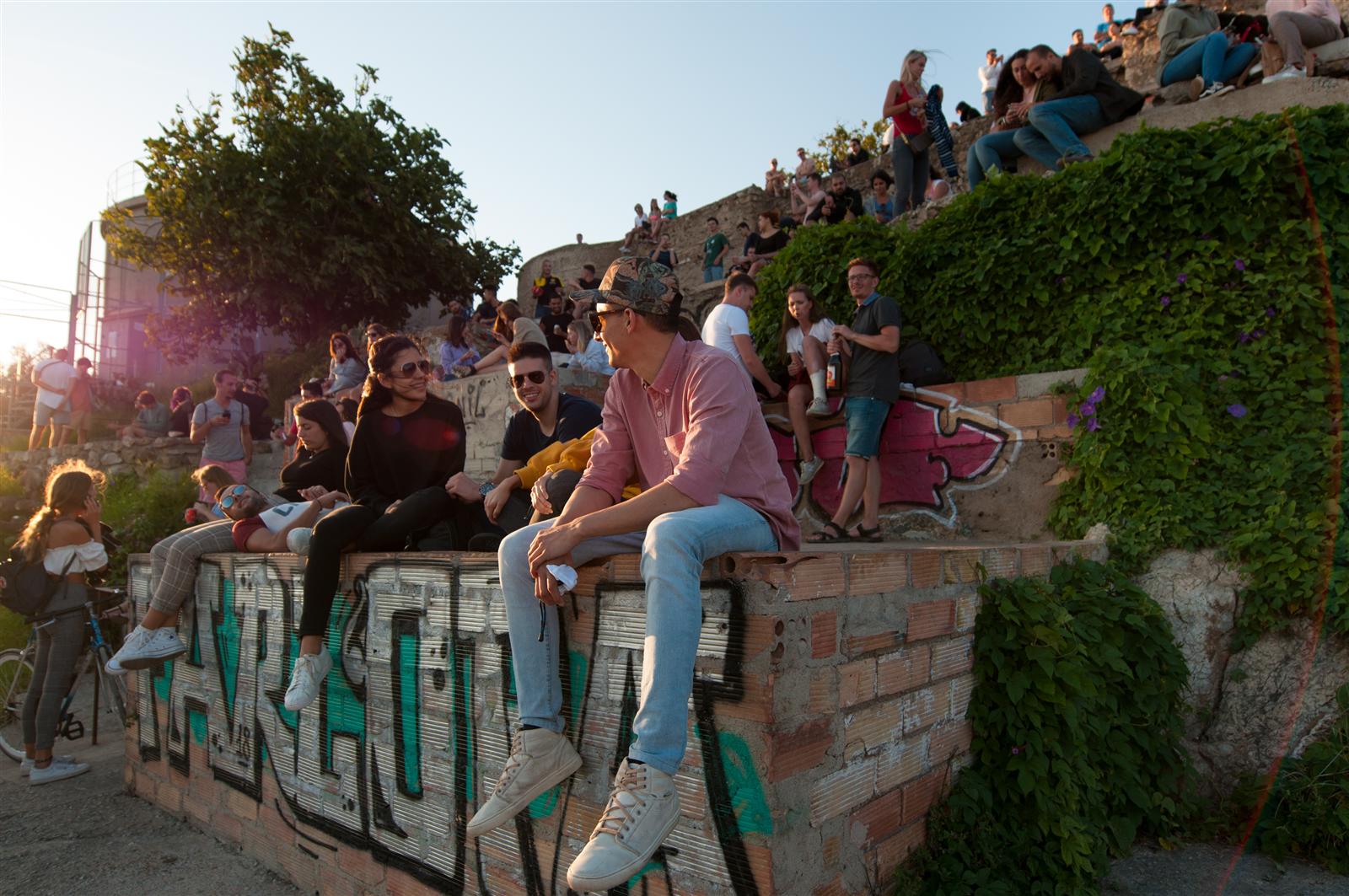 Ambiente social de tarde en los Bunkers del Carmel, gente sentada en el muro