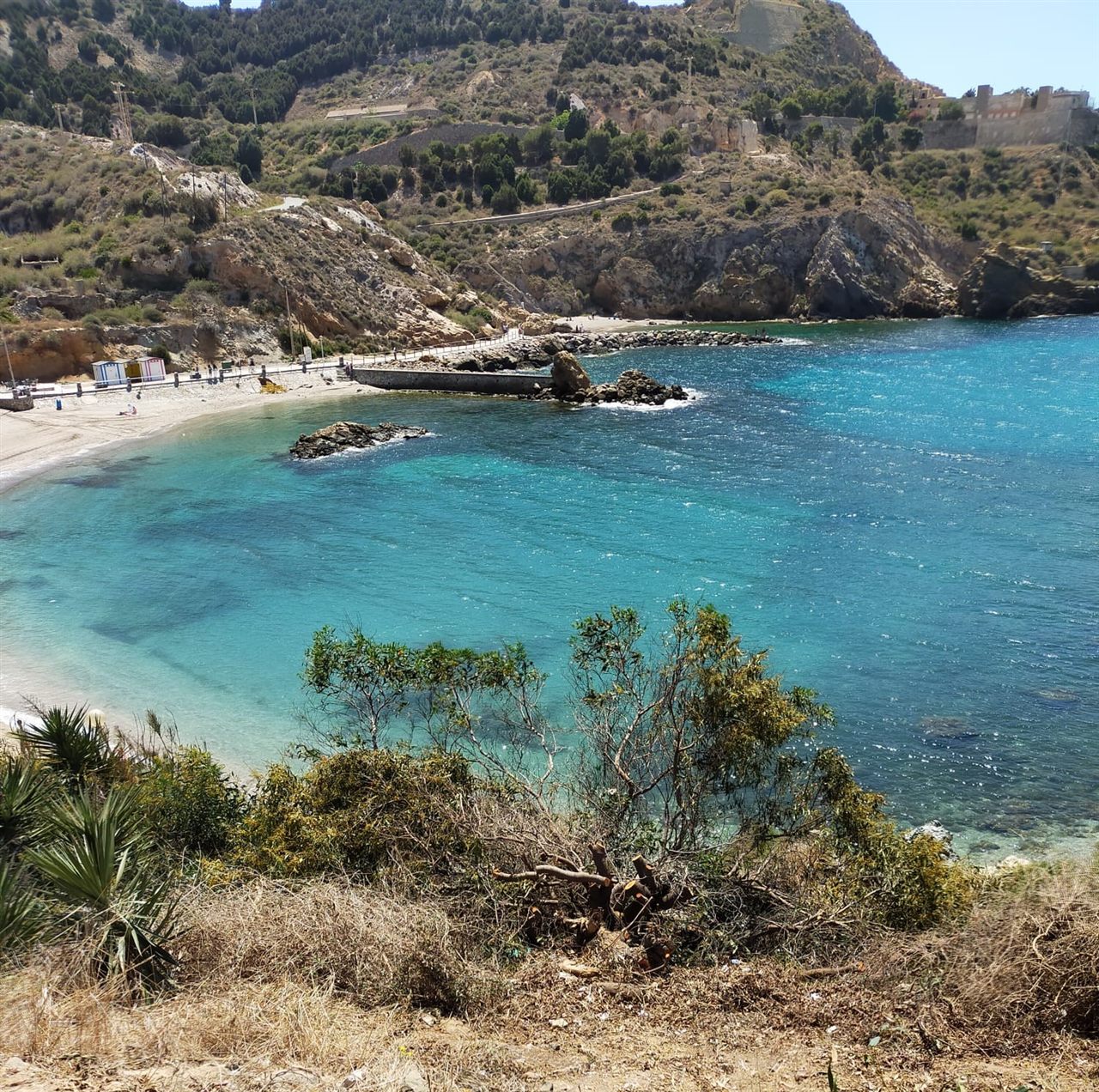 Vista de la Cala Cortina desde la orilla con el agua azul y la costa de Cartagena