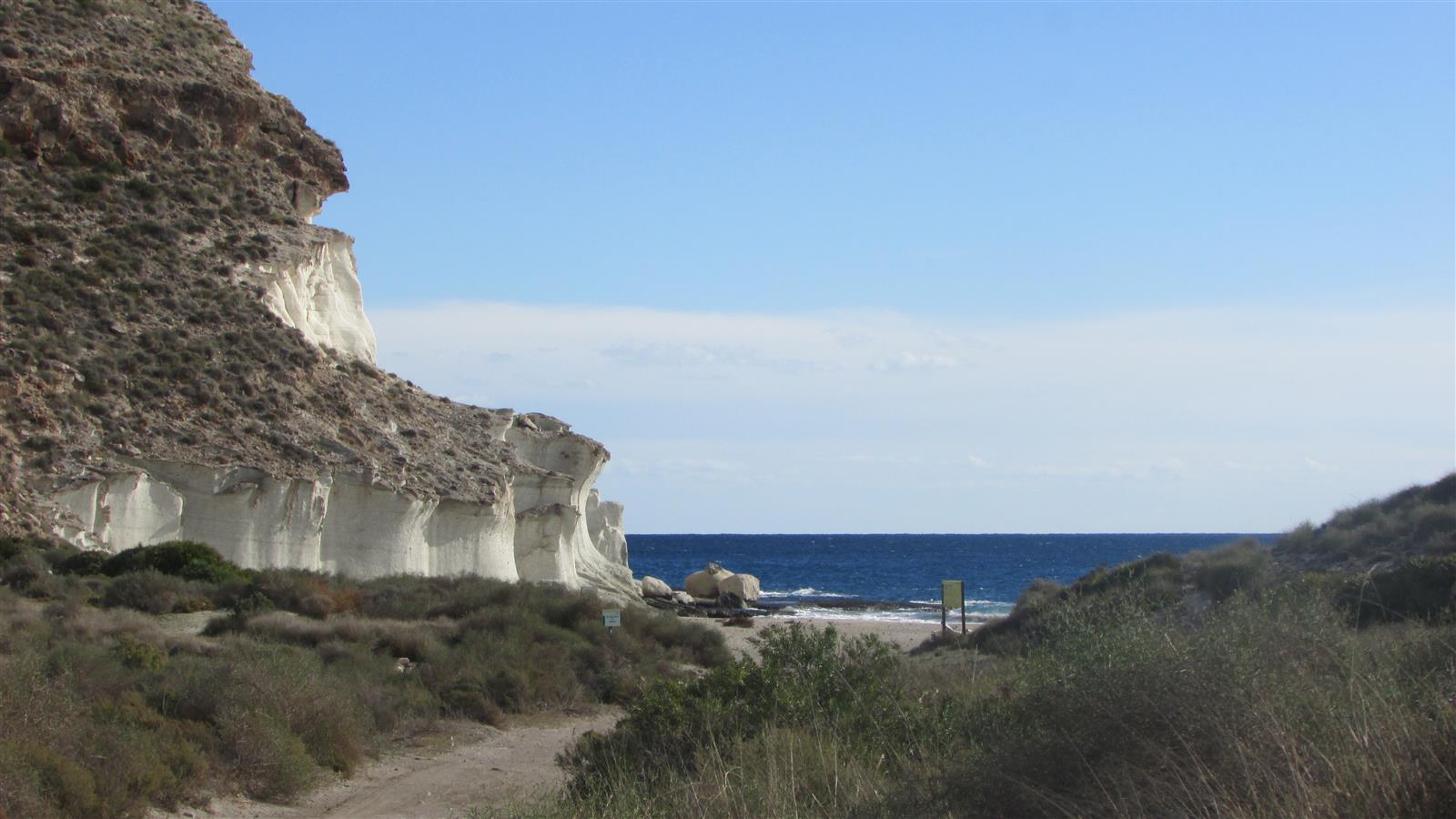 Camino de acceso a Cala de Enmedio con acantilados blancos volcánicos y el mar al fondo