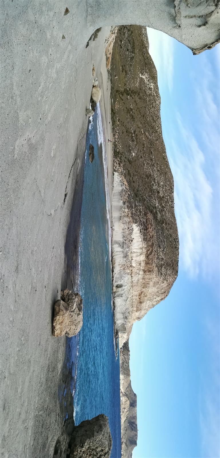Vista de Cala de Enmedio a través de un arco natural de roca volcánica blanca con agua turquesa