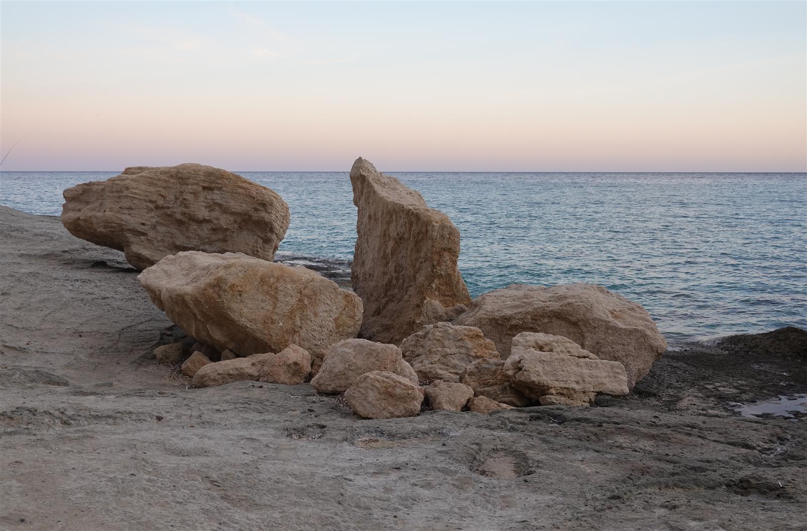 Rocas de calcarenita en la orilla de Cala del Plomo al atardecer con el mar en calma