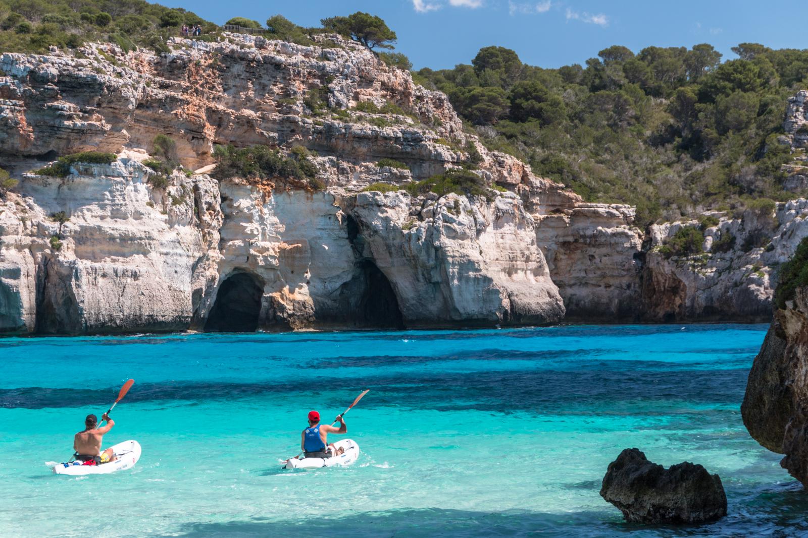 Piragüistas frente a las cuevas junto a Cala Macarelleta