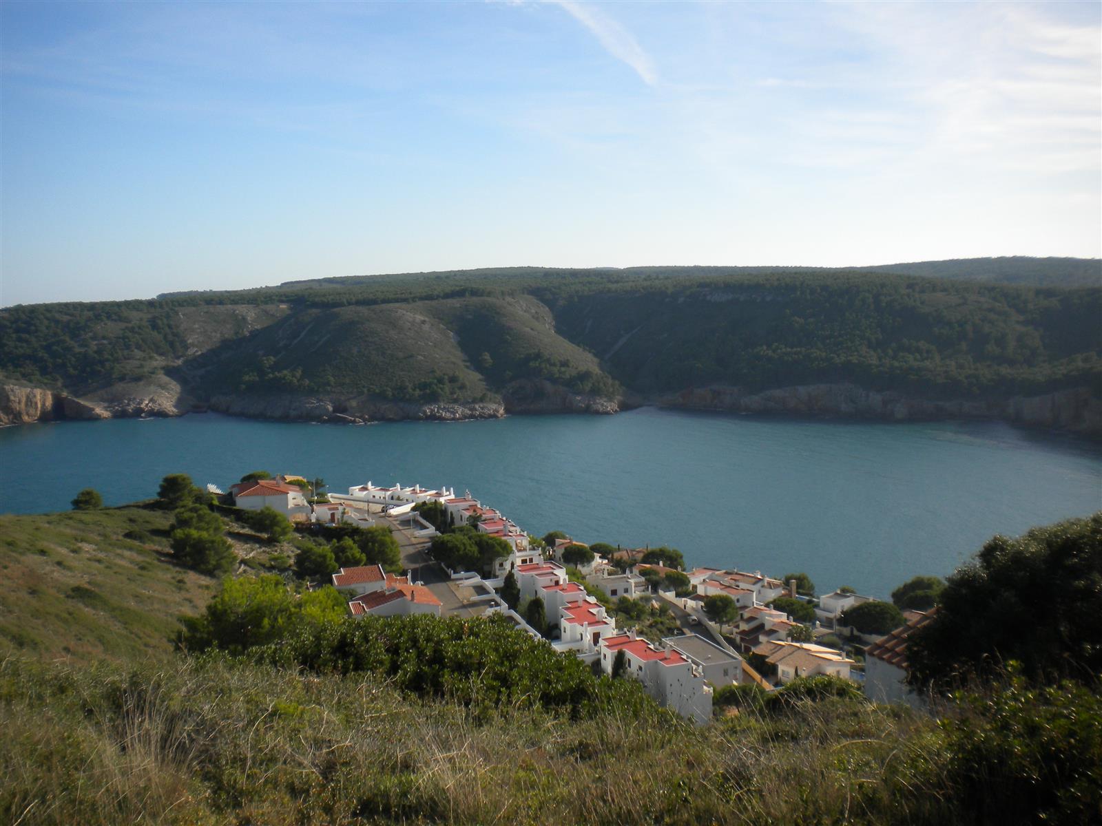Vista panorámica de Cala Montgó desde la Torre d'en Montgó con la urbanización, la bahía y las colinas de pinos al fondo