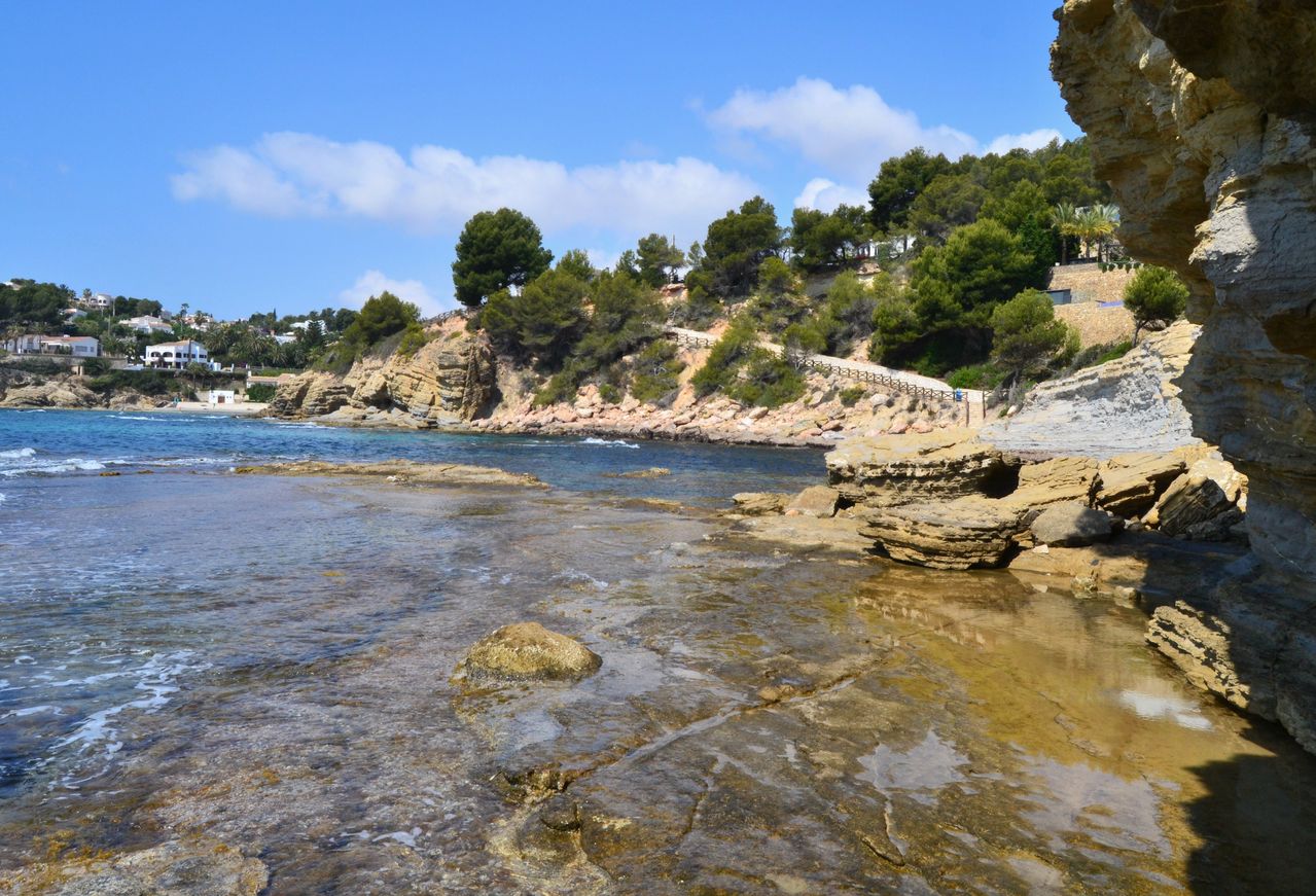 Vista de la Cala dels Pinets con sus formaciones de roca y agua cristalina en Benissa