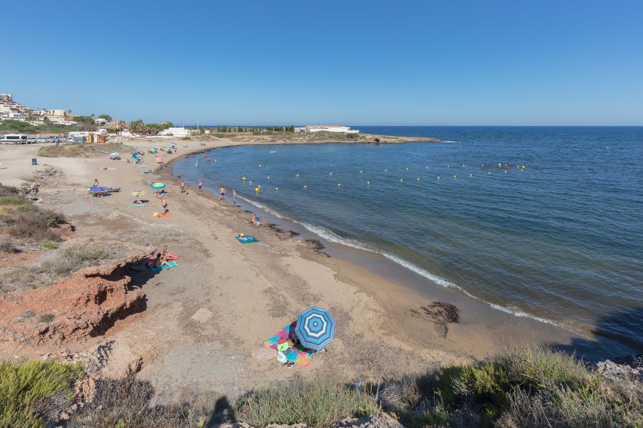 Bañistas en la Cala Reona junto a las rocas de pizarra negra
