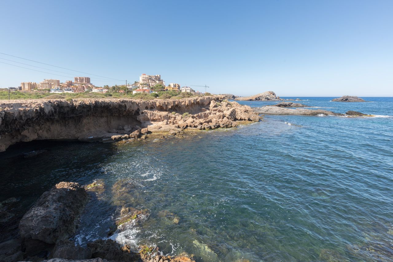 Vista de la Cala Reona con cantos negros de pizarra y agua cristalina en Cabo de Palos