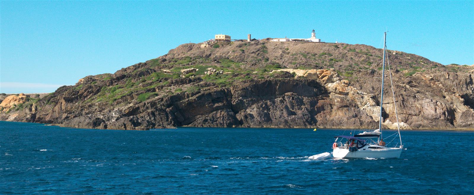 Faro y edificios de Cap de Creus en lo alto del cabo rocoso, vistos desde el mar, Costa Brava, Girona