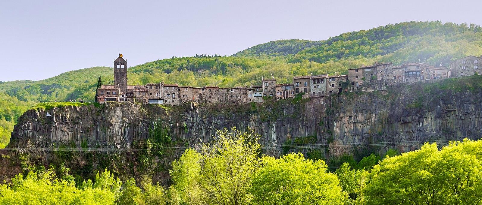 Vista de Castellfollit de la Roca en primavera sobre el acantilado de columnas basálticas, con vegetación nueva y cielo despejado