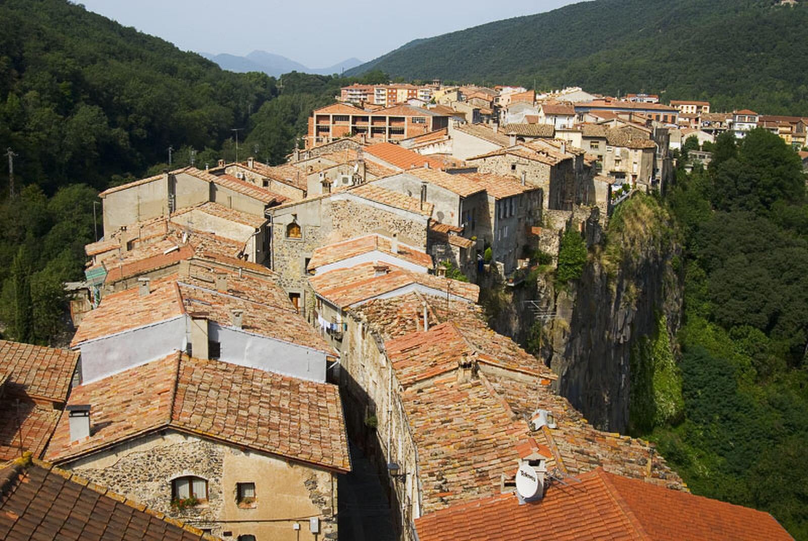 Vista aérea desde el campanario de Castellfollit de la Roca: tejados de tejas naranjas y el borde del risco basáltico sobre el valle del Fluvià