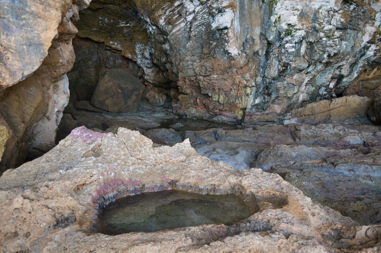 Interior de la Cova Tallada con la bassa de agua y las paredes de roca, Xàbia