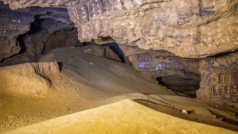 Interior de la Cova Tallada con luz cálida sobre la roca, Alicante