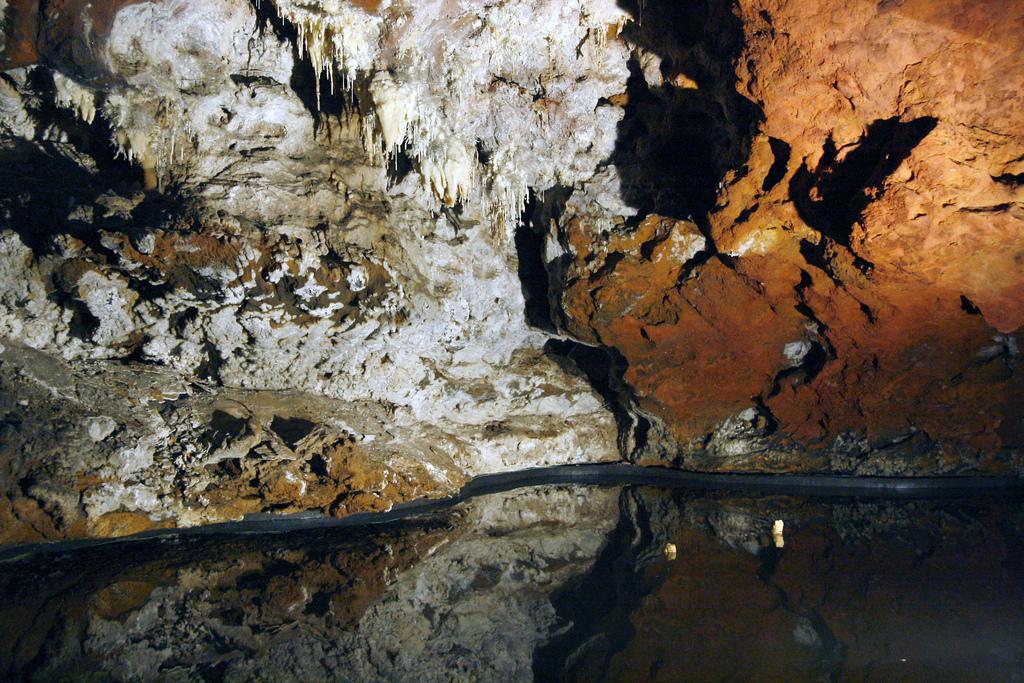 Galería con laguna subterránea y formaciones ferruginosas de tonos anaranjados