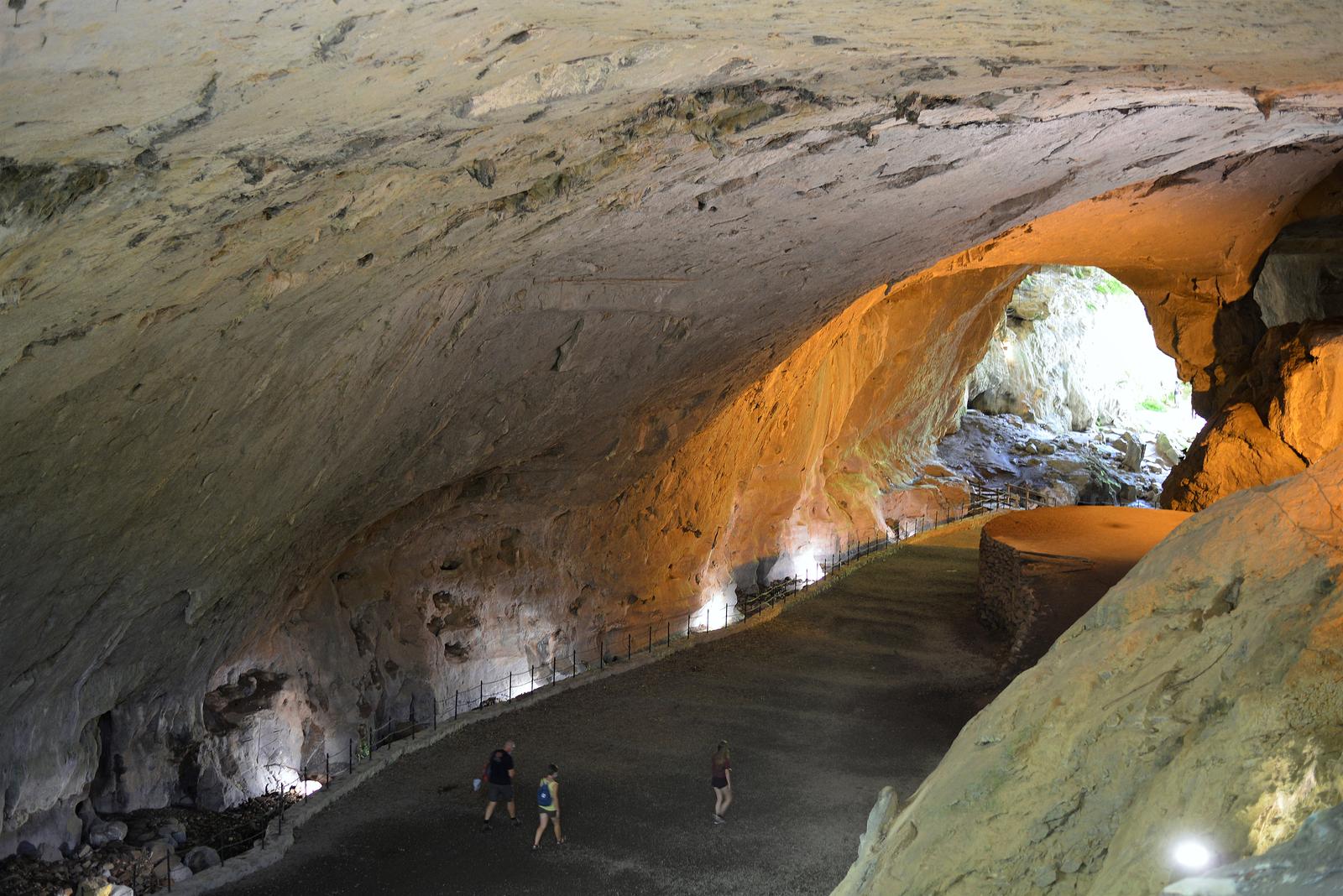 Interior de las Cuevas de Zugarramurdi con luz natural entrando por la bóveda calcárea y el arroyo en el suelo