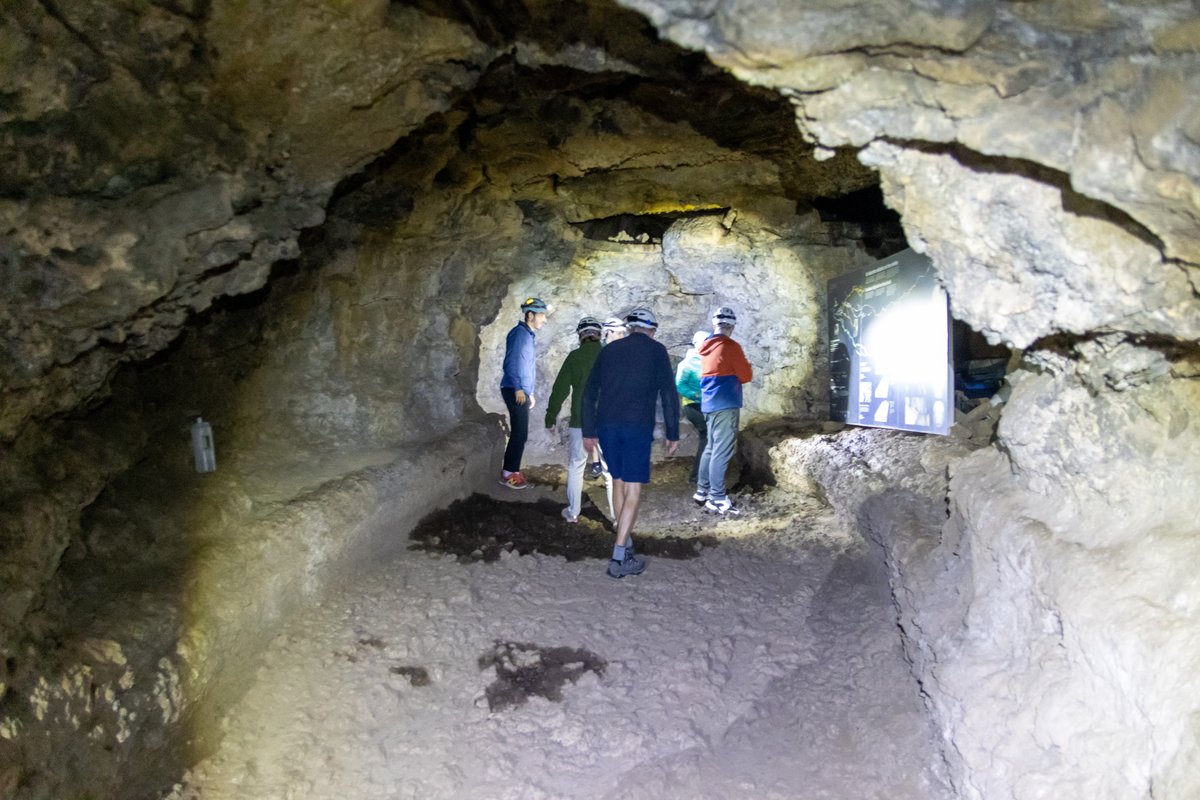 Galería principal de la Cueva del Viento, Tenerife: suelo de lava cordada y paredes volcánicas con guías iluminando el camino