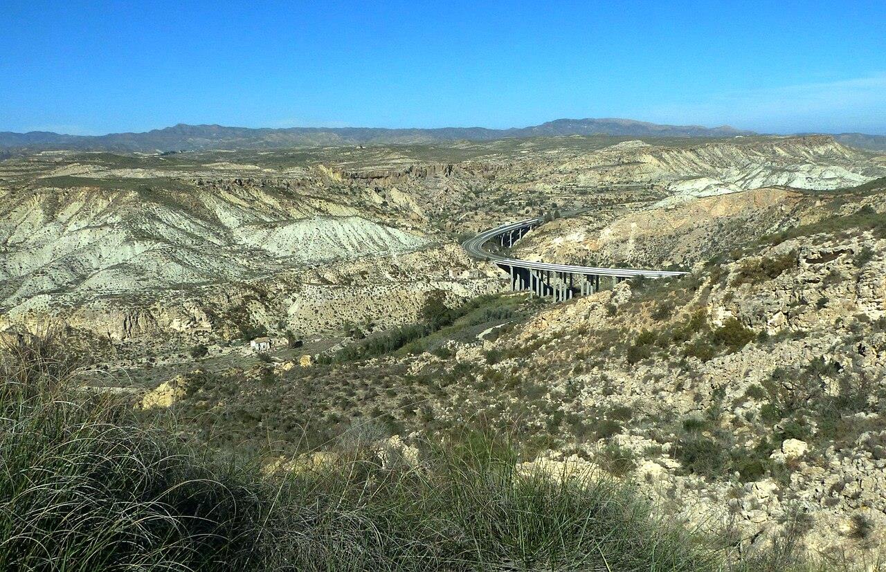 Paisaje kárstico en yesos de Sorbas desde las colinas, con el característico terreno blanco y ocre y el viaducto de la autovía al fondo, Almería