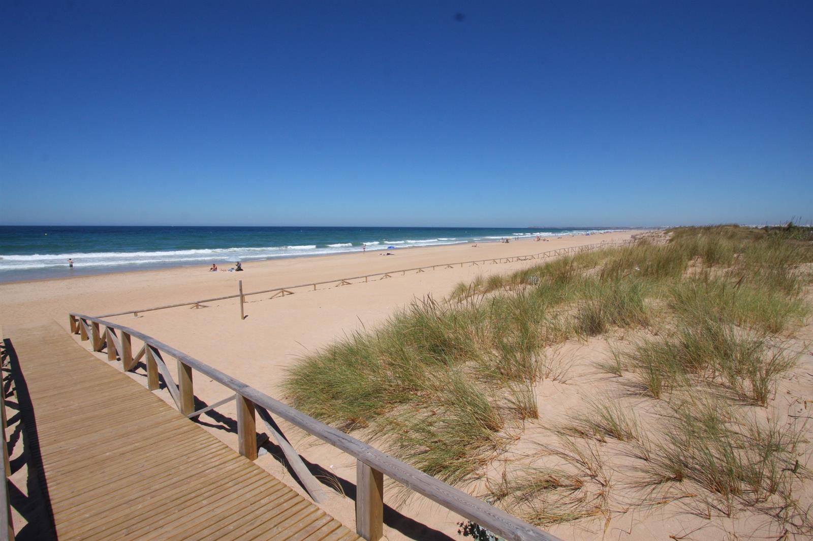 Pasarela de acceso a la playa de El Palmar con dunas de arena a los lados