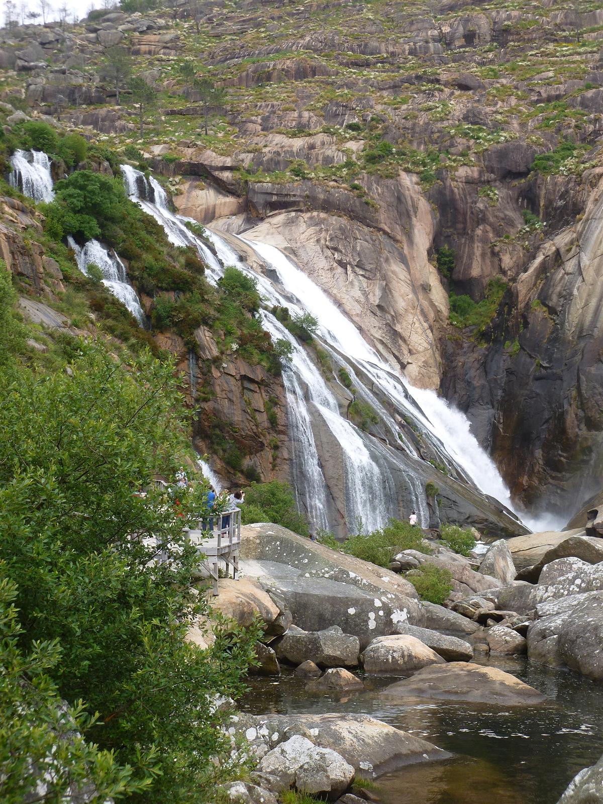 Visitantes en la pasarela de madera junto a la cascada
