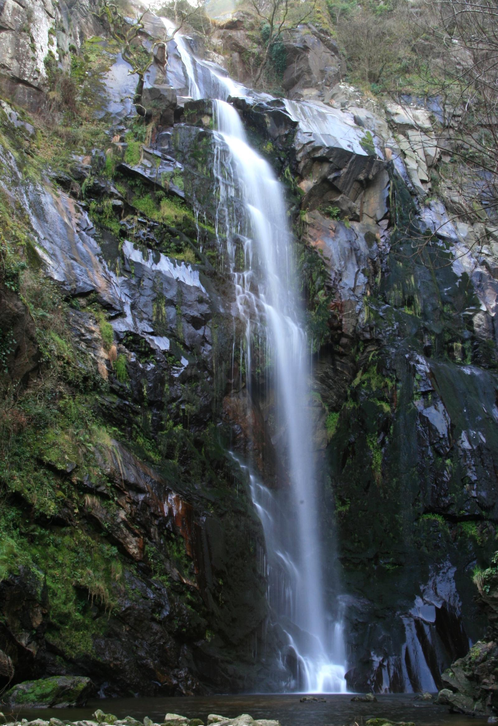 Cascada escalonada entre rocas musgosas en A Moa