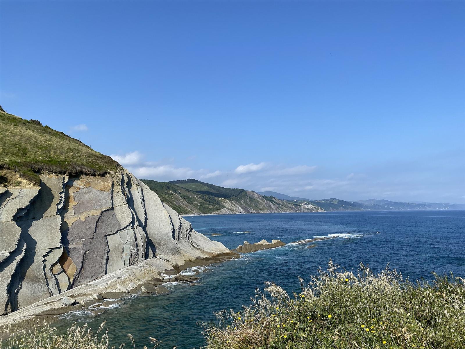 Estratos del flysch en punta Algorri, Zumaia, con el acantilado y el mar Cantábrico