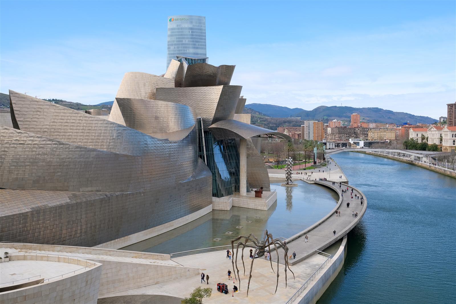 Exterior del Museo Guggenheim Bilbao con su estructura de titanio y cristal en día despejado, vista lateral de las curvas orgánicas del edificio de Gehry, Bilbao