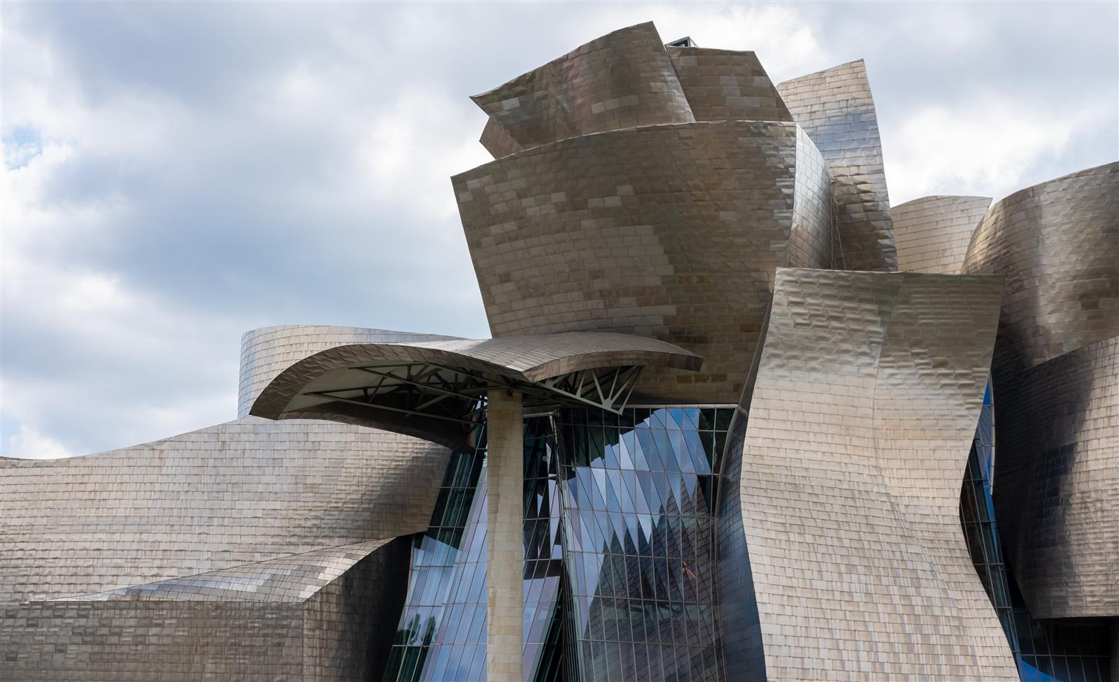 Fachada norte del Museo Guggenheim Bilbao con las placas de titanio brillando bajo la luz del día, curvas y volúmenes de la arquitectura de Frank Gehry, Bilbao, País Vasco