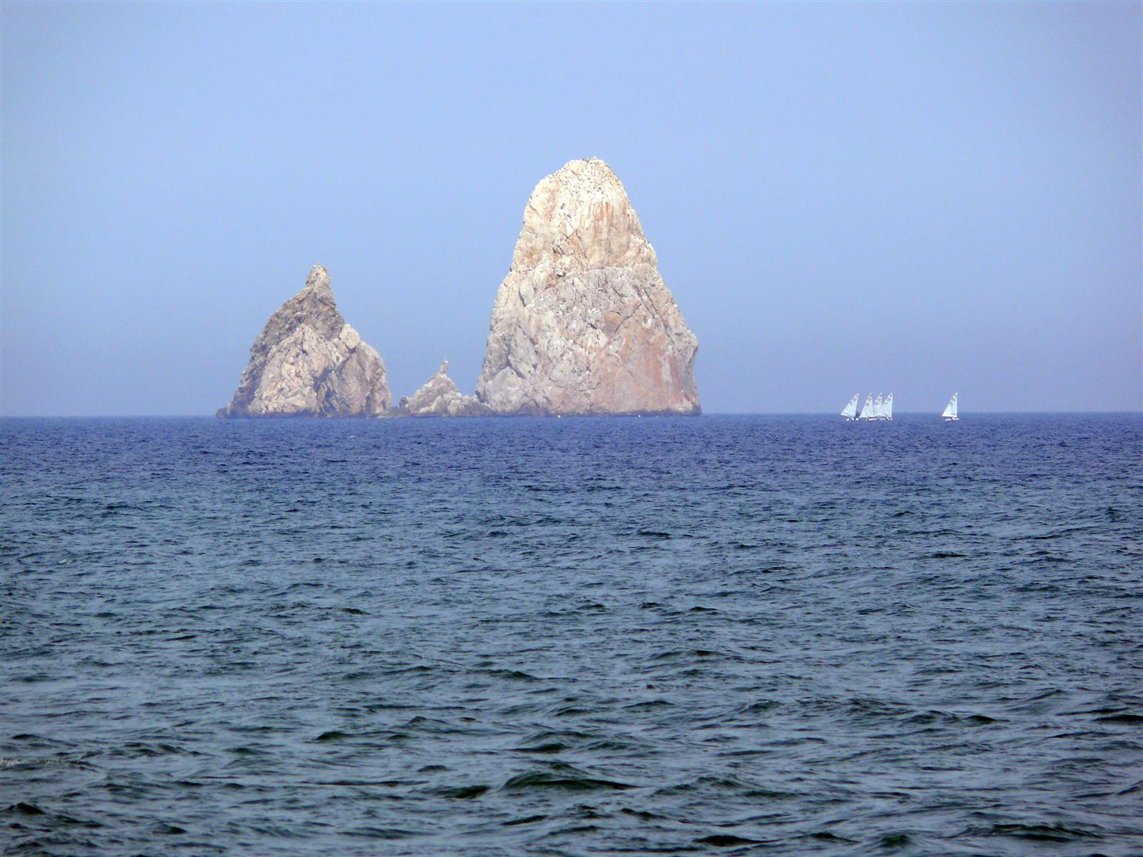 Los Tascons, farallones rocosos icónicos de las Illes Medes con veleros al fondo sobre el mar azul mediterráneo, Girona