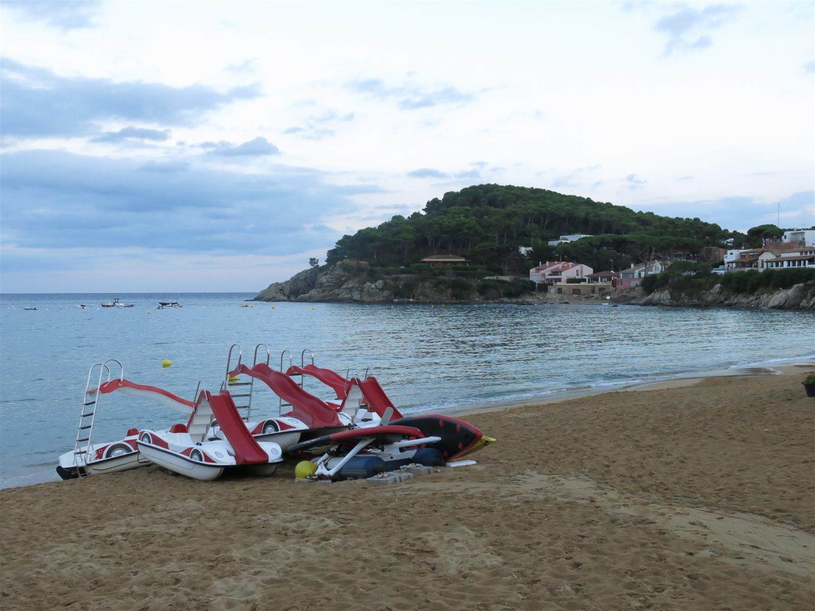 Playa de La Fosca con el cap Gros al fondo y hamacas y triboats en la orilla, Palamós, Girona