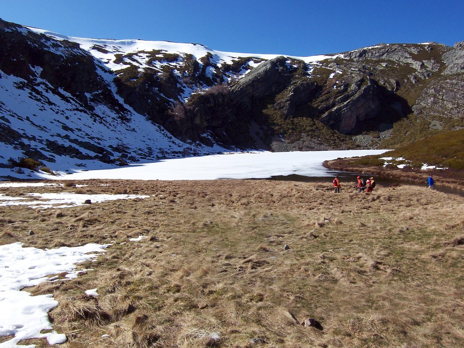 Lago con nieve y senderistas en la orilla
