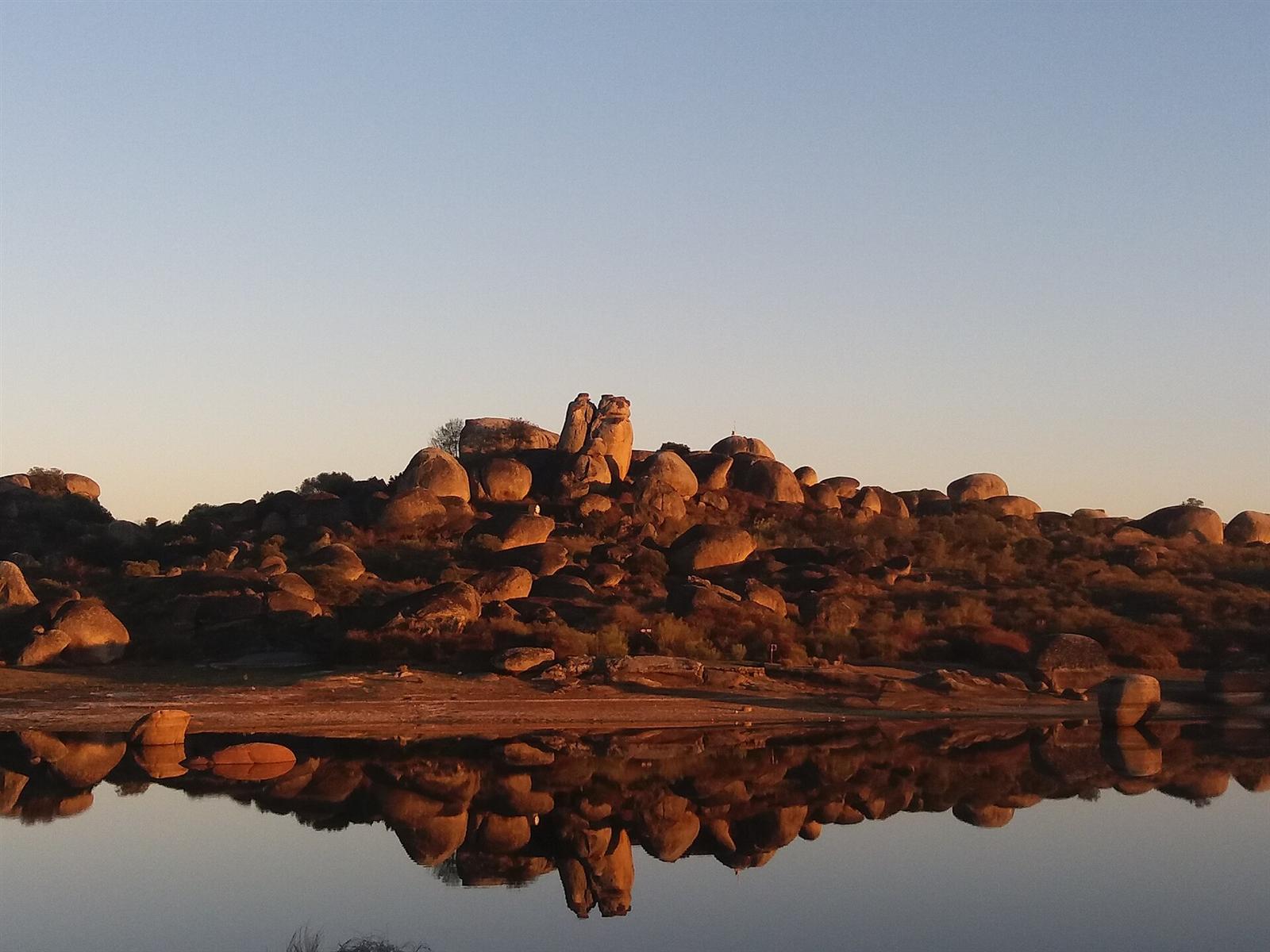 Grandes bolos graníticos de Los Barruecos reflejados en el agua de la charca