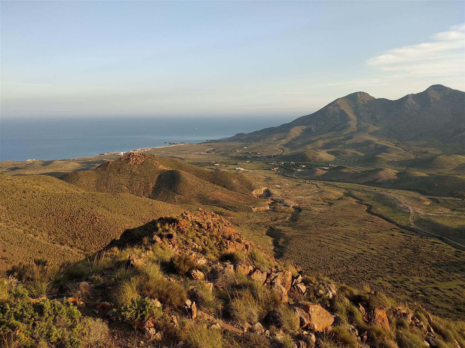 Vista panorámica aérea desde el Cerro de los Frailes sobre Los Escullos, con la playa al fondo y el Mediterráneo en el horizonte al atardecer