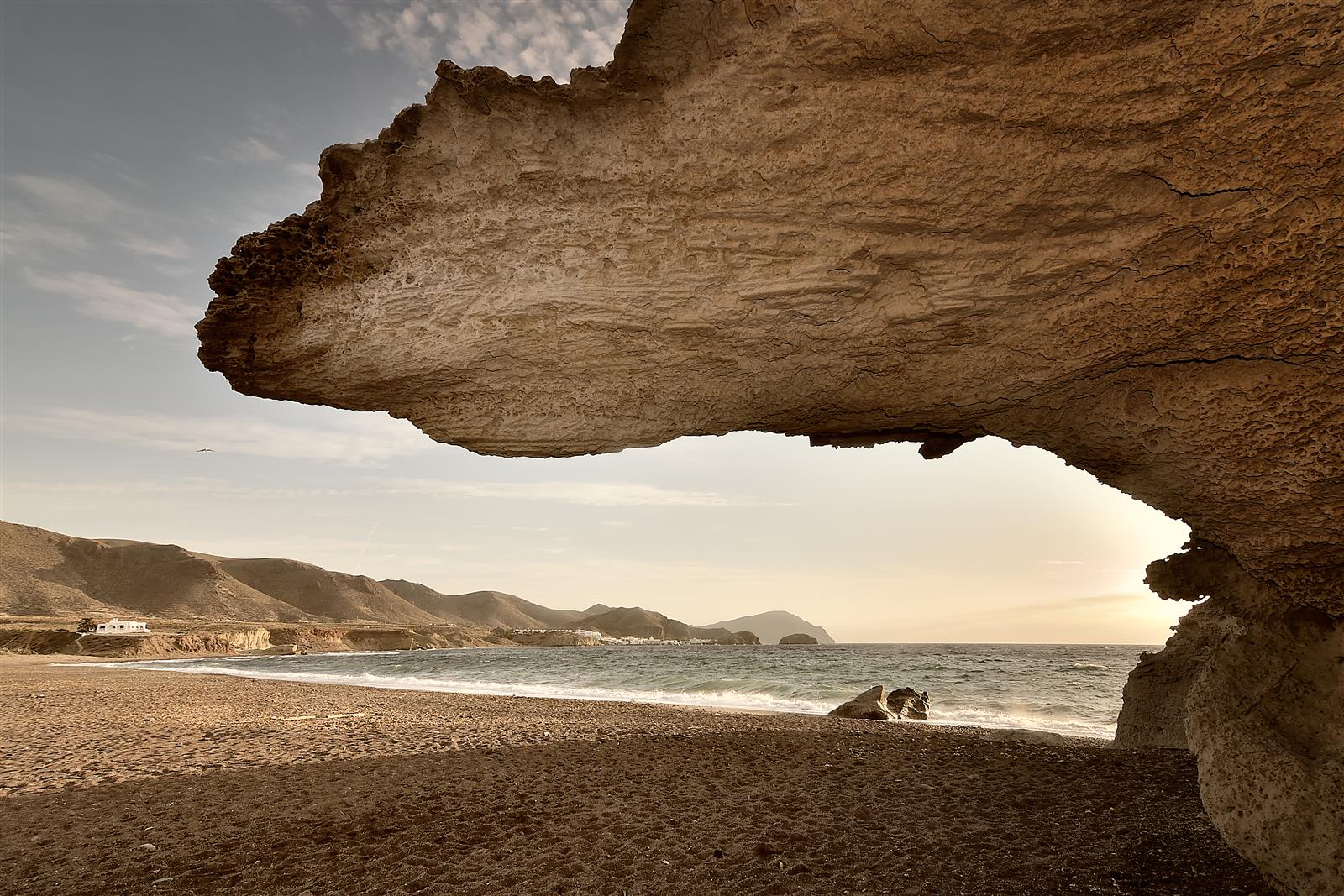 Vista desde el interior de la duna fósil de Los Escullos encuadrando la playa de arena oscura, el mar y los montes volcánicos del Cabo de Gata al atardecer