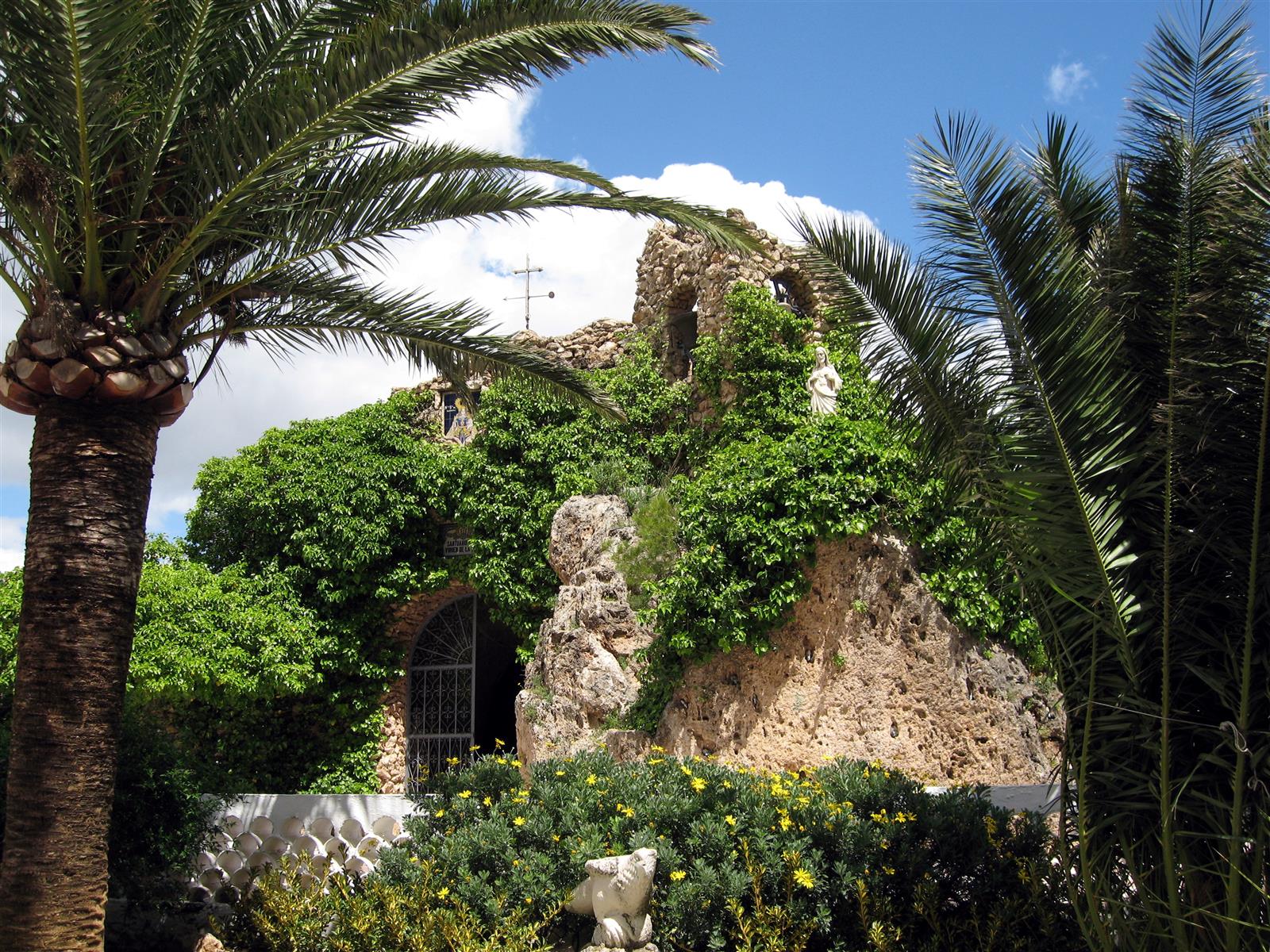 Ermita de la Virgen de la Peña de Mijas, capilla excavada en la roca viva entre palmeras, Málaga