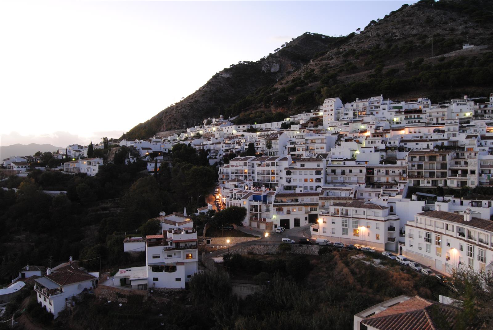 Mijas Pueblo al atardecer, vista exterior de las casas blancas en la ladera con la Sierra al fondo, Málaga