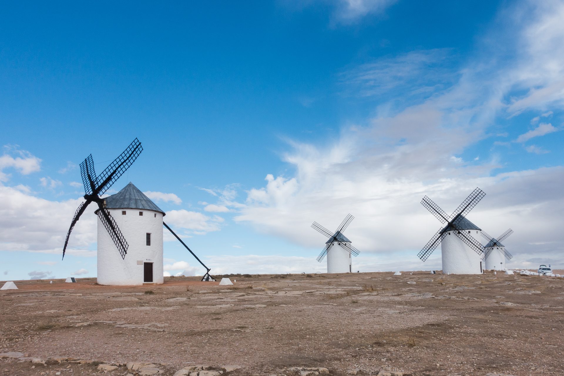 Vista lateral de los molinos de Campo de Criptana con las aspas de madera bajo el cielo azul