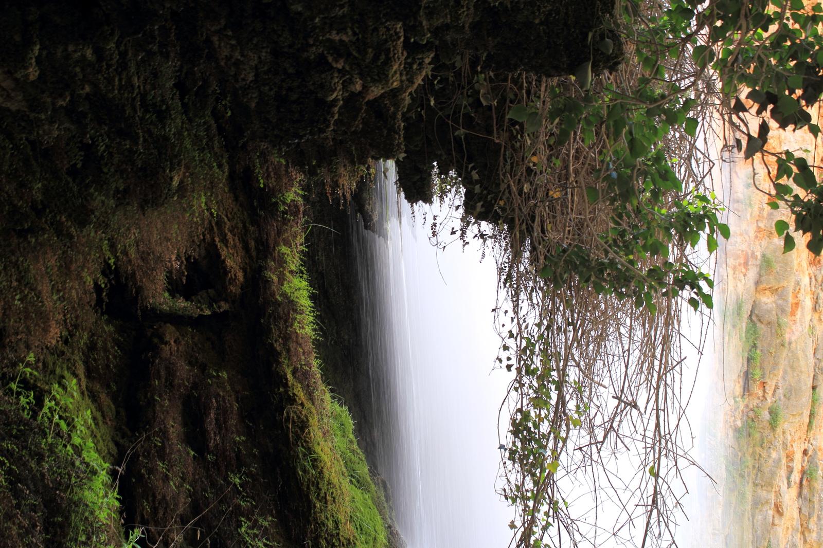 Cascada vista desde debajo de la gruta, entre vegetación