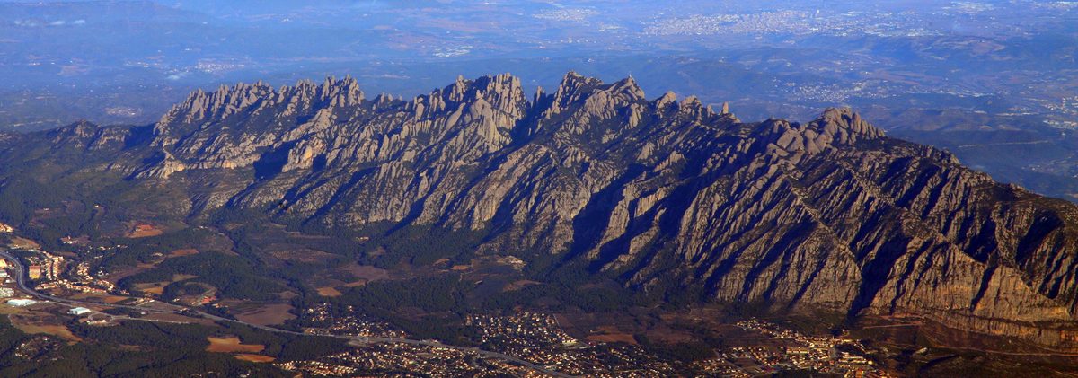 Panorámica de Montserrat desde el valle: silueta del macizo recortada contra el cielo con los Pirineos al fondo