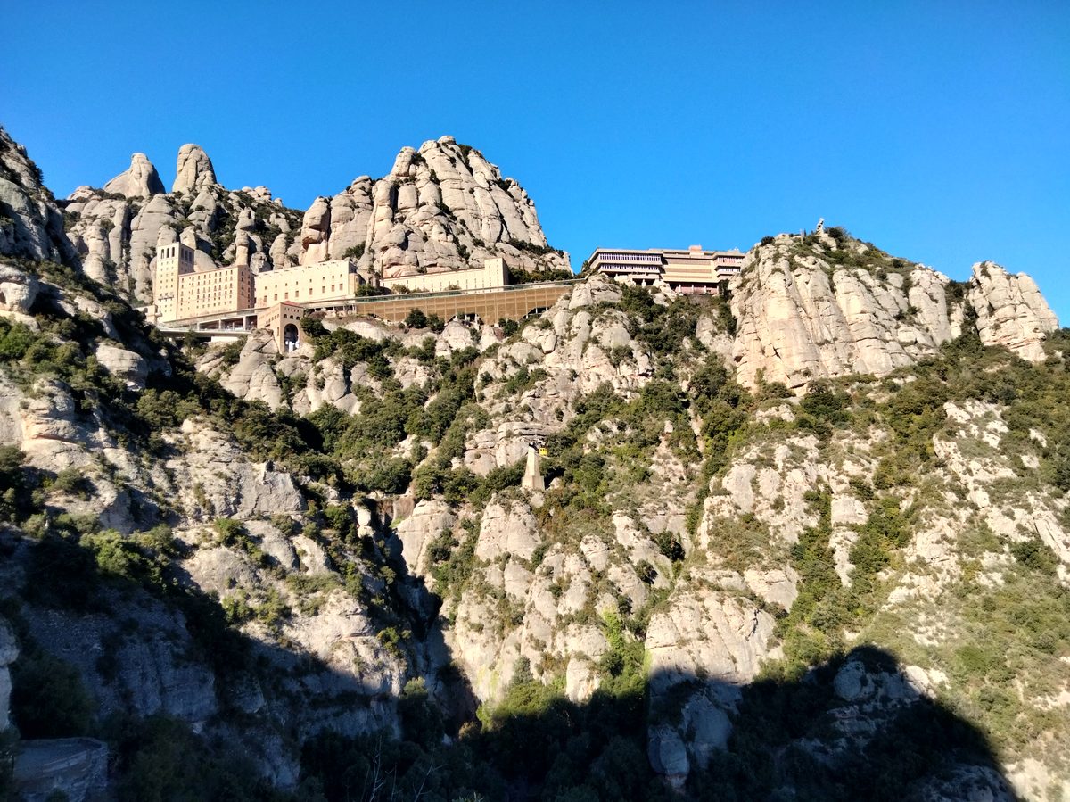 Monasterio de Santa Maria de Montserrat con las rocas del macizo al fondo, visto desde el Camí de la Santa Cova