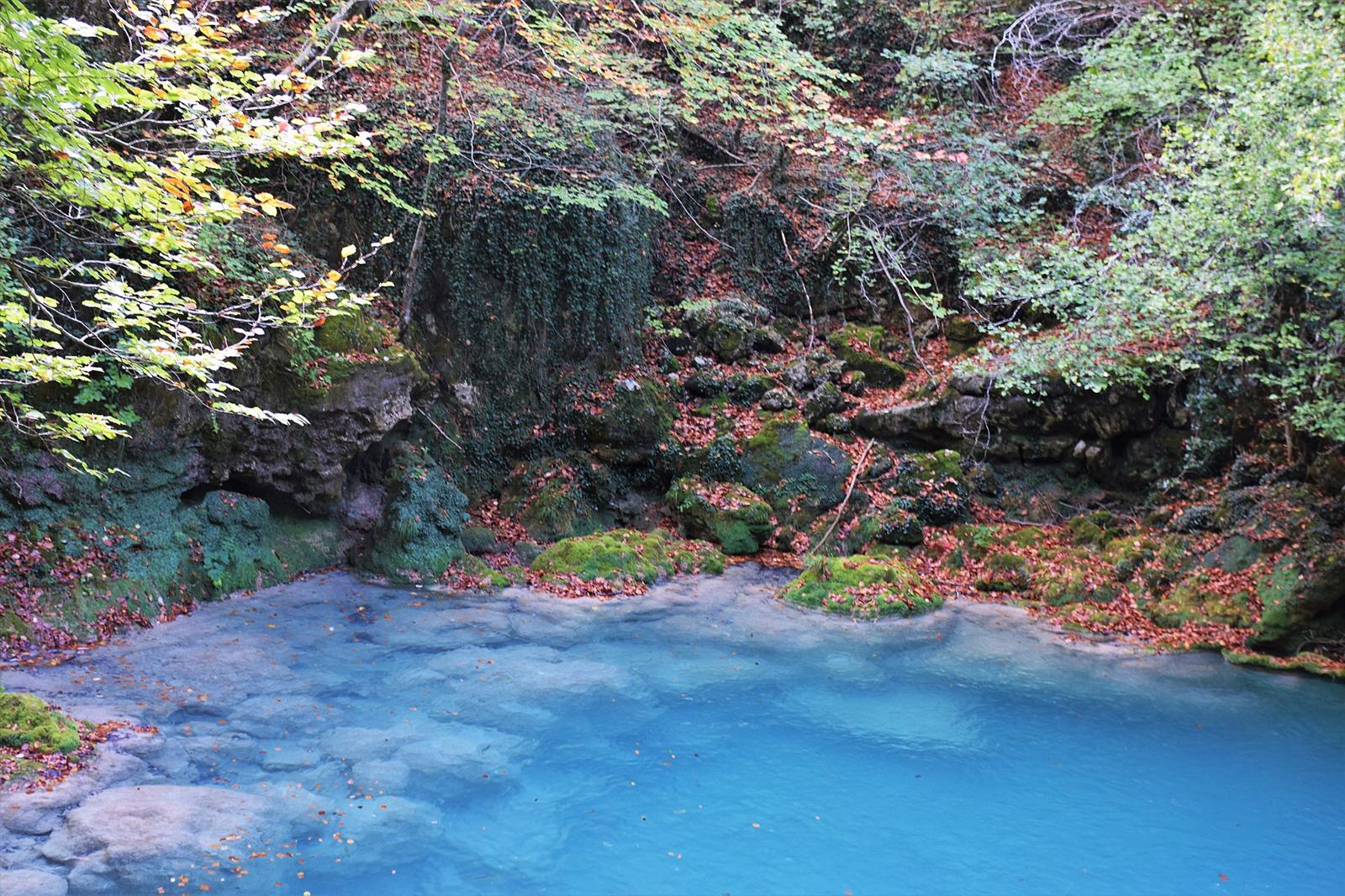 Poza de aguas turquesas y esmeralda junto al sendero