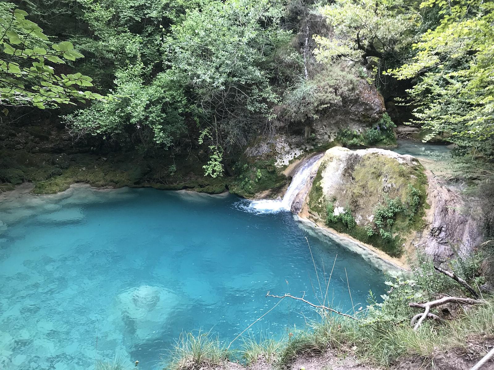 Poza de aguas turquesas con cascada en el Nacedero del Urederra