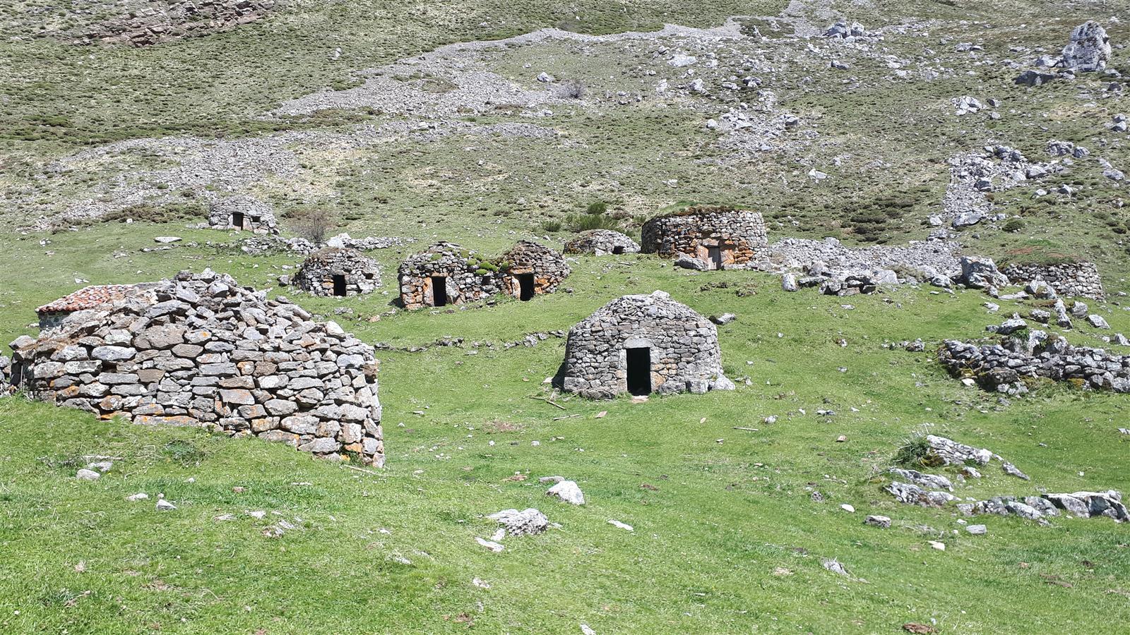 Braña de Sousas en el Valle del Lago de Somiedo, Asturias, con cabañas de teito y montañas al fondo