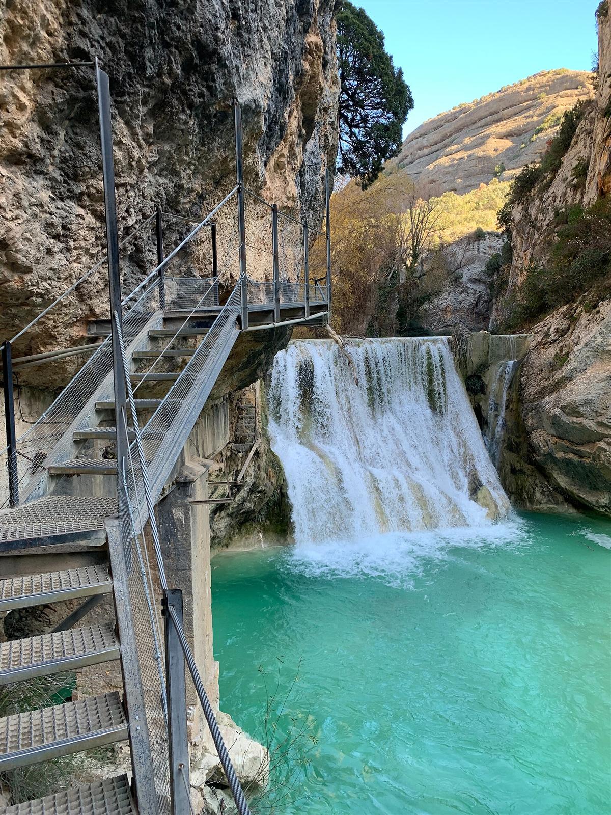 Detalle de la pasarela metálica y el azud con salto de agua