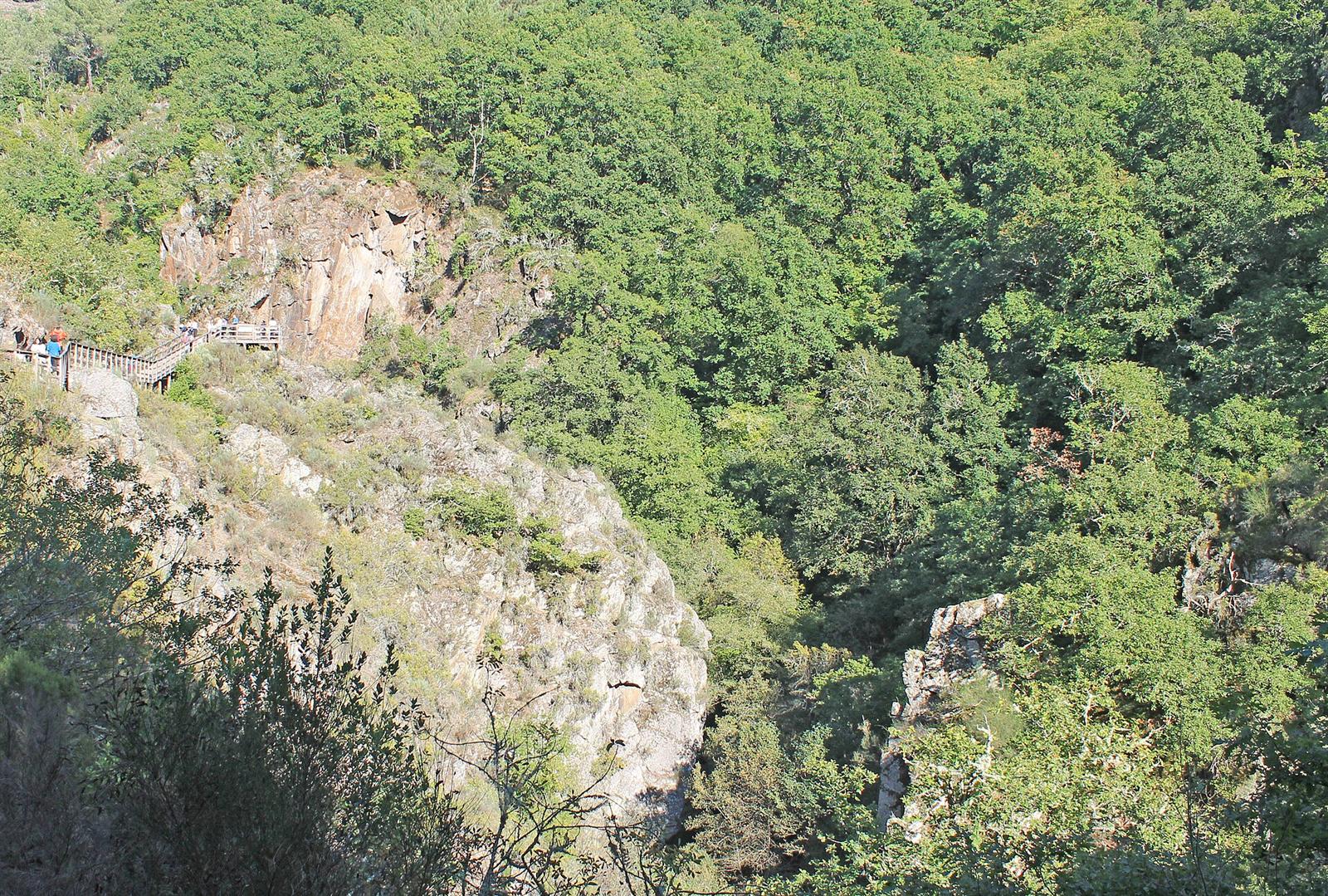 Pasarela de madera fijada a la pared del cañón del río Mao, con visitantes recorriéndola