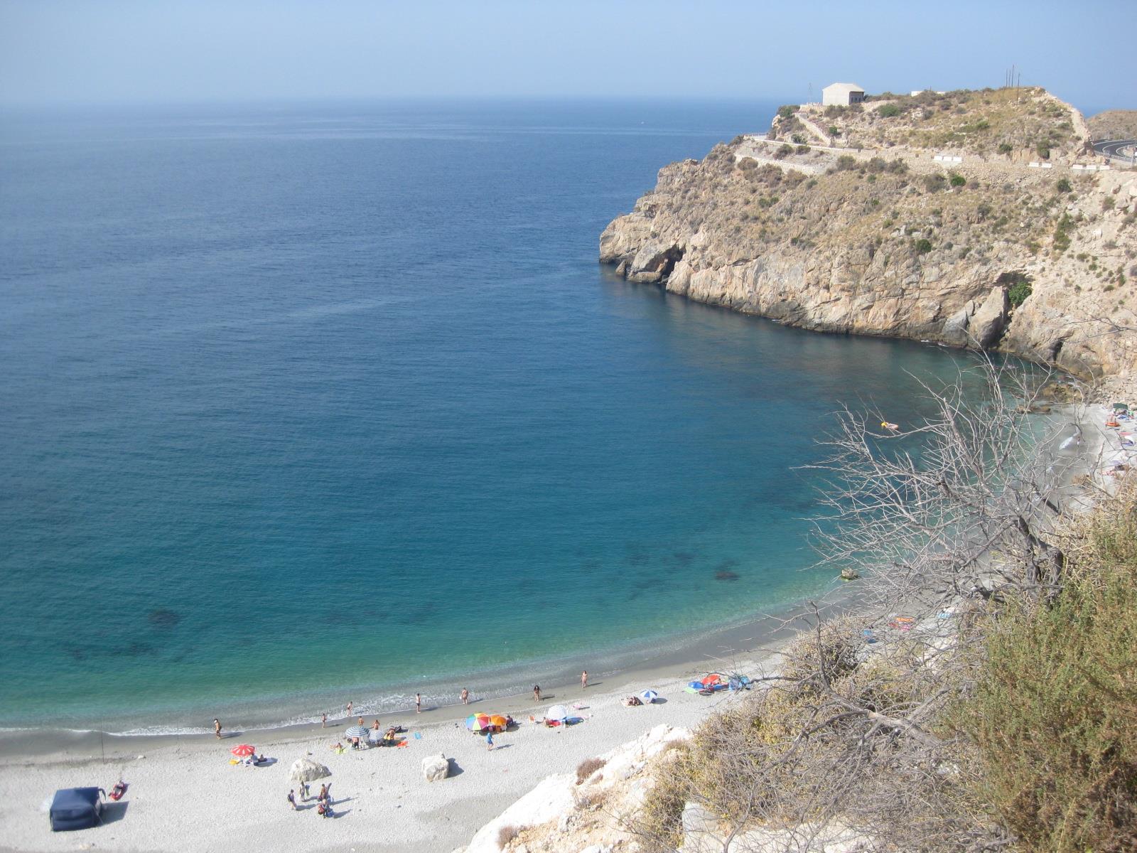 Playa de La Rijana en julio de 2013 desde un ángulo distinto, con la orilla de canto, el agua azul y el acantilado al fondo