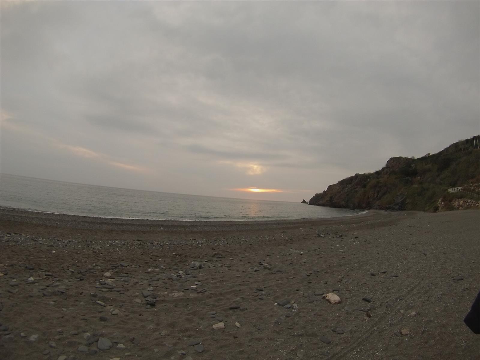 Playa de Maro en día de borrasca con cielo nublado y acantilados al fondo, mostrando el entorno natural en invierno