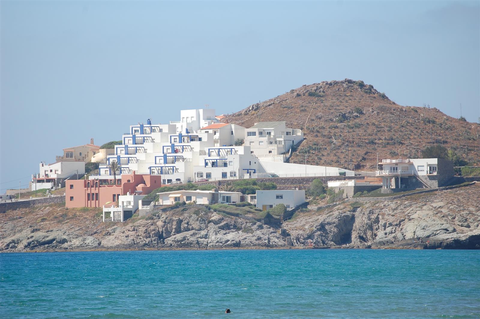 Promontorio de San José visto desde el mar con construcciones blancas escalonadas sobre roca volcánica y agua turquesa